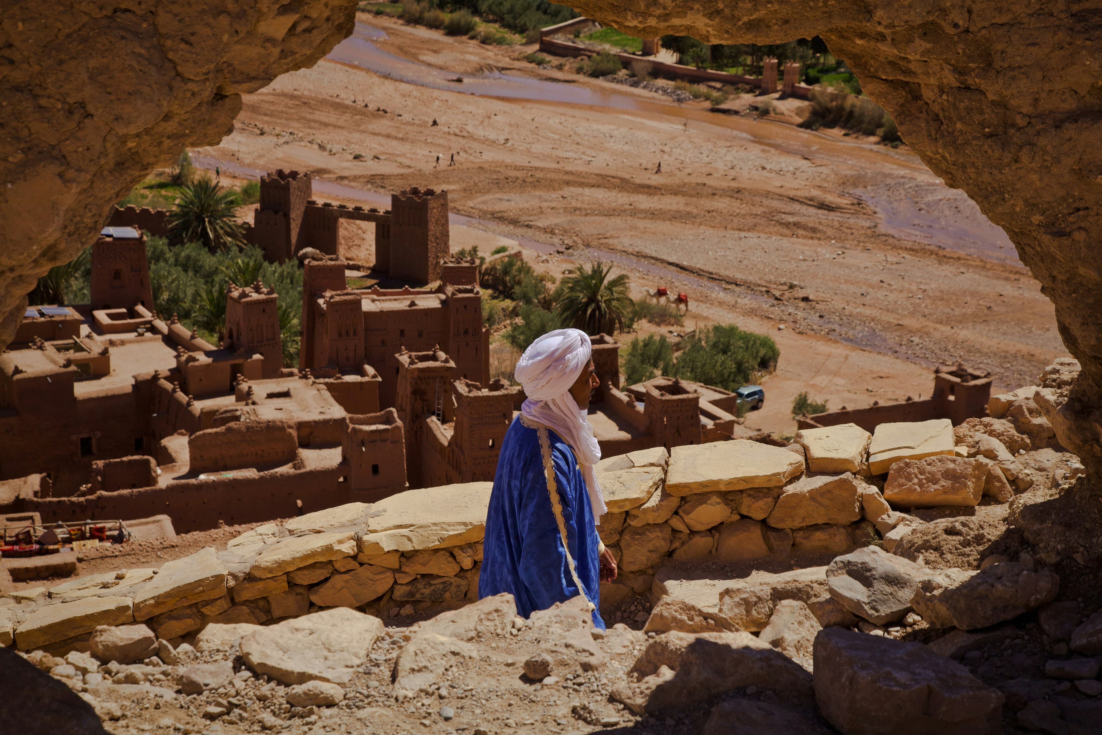 Berber guide in traditional robe with High Atlas kasbah landscape, Morocco