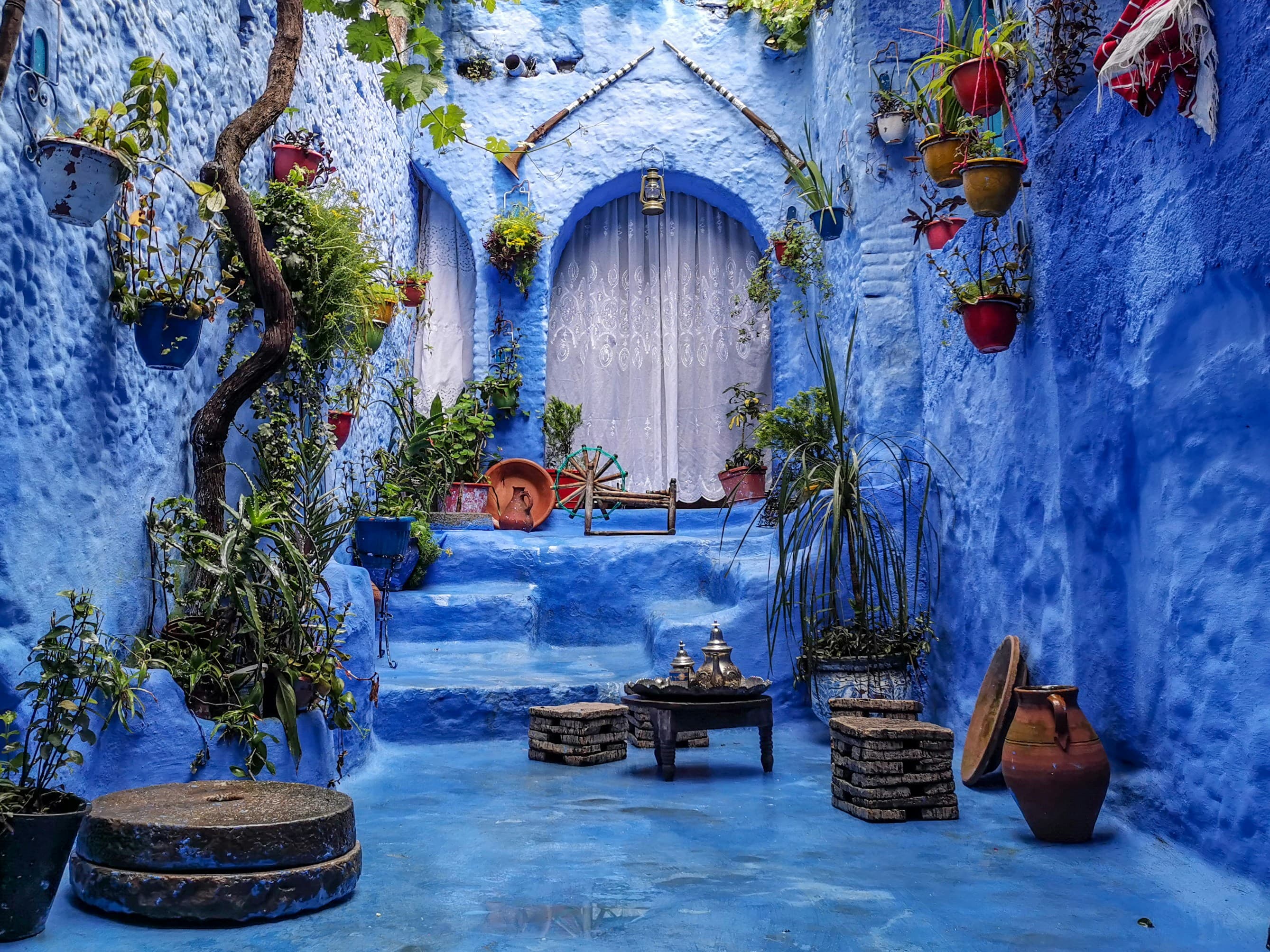 Blue courtyard with hanging plants and a tea table in Chefchaouen medina