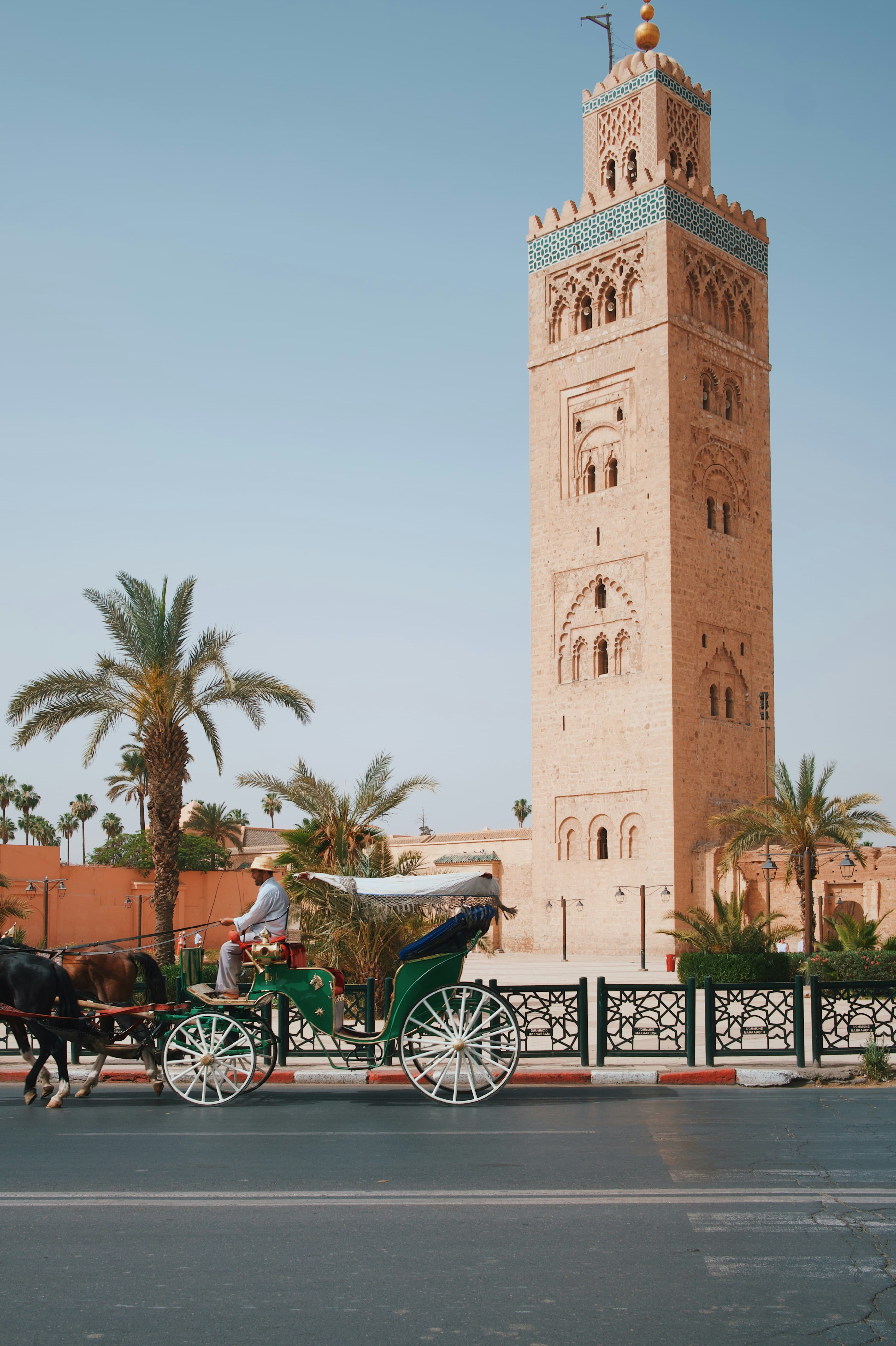 Horse-drawn carriage (calèche) passing the Koutoubia Mosque minaret at dusk, Marrakech