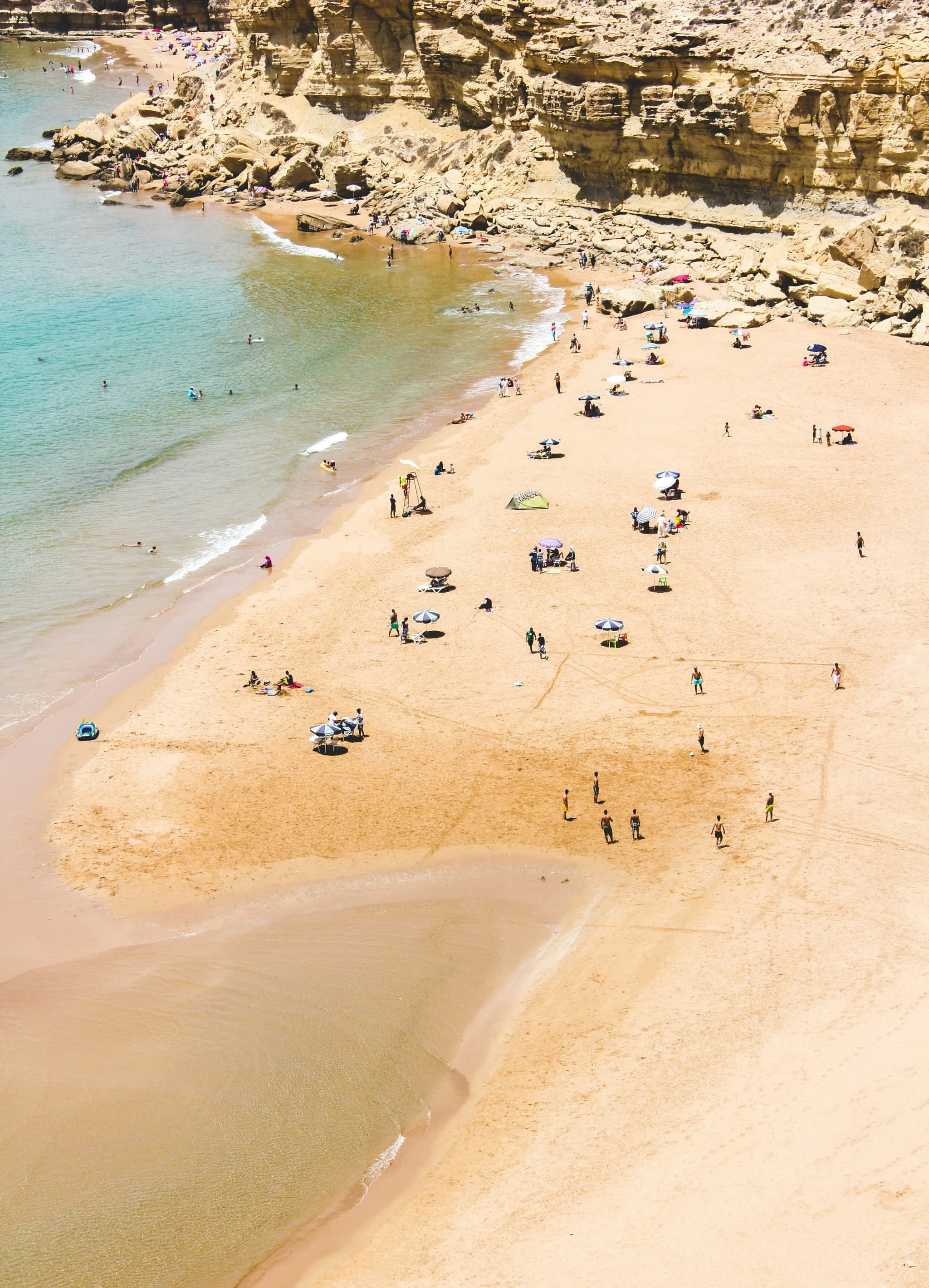 Aerial view of Agadir's golden sandy beach with swimmers and beach umbrellas along the Atlantic coast, Morocco
